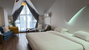 A modern hotel room with a large bed, a sofa, a chair, and a desk. There is a window with curtains and a pendant light. - Zhangjiajie YunYe Hotel (Zhangjiajie)