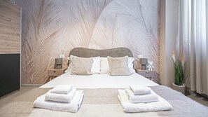 Une chambre à coucher moderne avec un grand lit, deux tables de chevet, une lampe fixée au mur et un vase avec des plantes.
