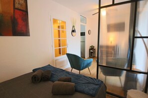 A room with a bed, a chair, a window, and a door. - Studio 25 m², centre-ville, avec balcon et wifi (Aix-les-Bains)