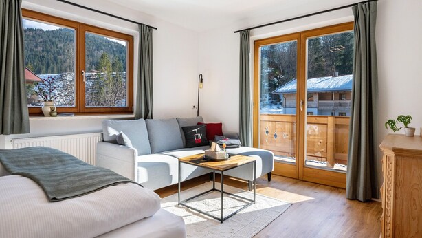 A modern living room with a sofa, a coffee table, and a view of a snowy mountain. - Apartment 'Fewo Am Steinbach - Stoaboch' with Mountain View, Balcony and Wi-Fi (Reit im Winkl)