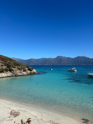 A coastal landscape with clear turquoise waters, boats, and distant mountains. - Charming 3-Bedroom Villa with Private Heated Pool (Barbaggio)