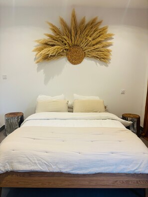 Ein Schlafzimmer mit einem großen Bett, zwei Nachttischen und einem dekorativen Wandbild darüber.