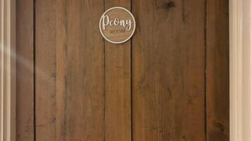 Een houten wand met een rond bord waarop 'Peony Room' staat.