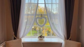 Una habitación con una ventana, un adorno con forma de corazón y un cuenco en el alféizar.