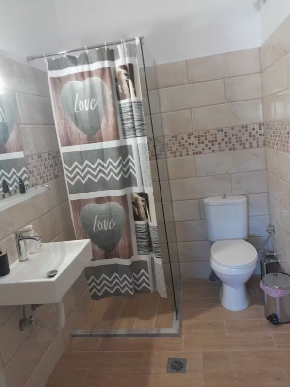 A bathroom with a shower curtain featuring 'Love' and zigzag patterns, a white sink, and a toilet.