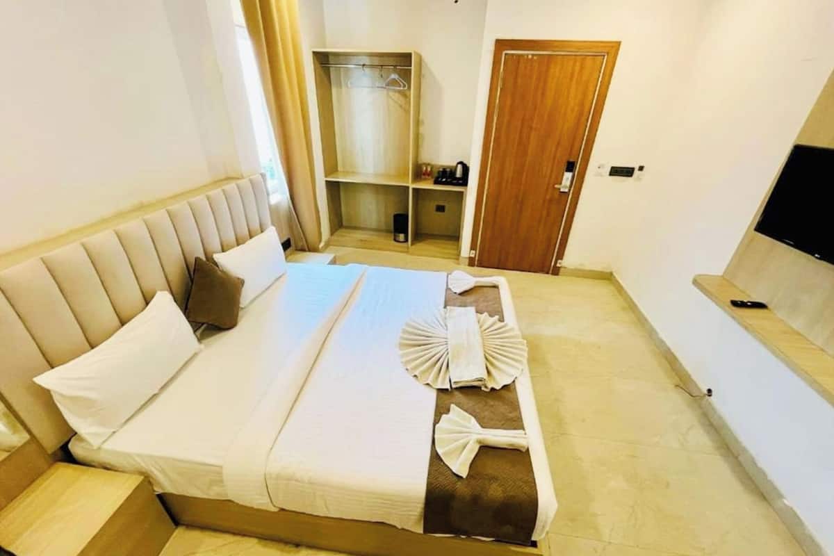 A hotel room with a bed, a TV, a wardrobe, and a small seating area.
