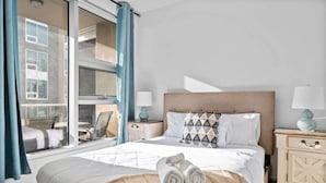 Ein Hotelzimmer mit Bett, Fenster, Nachttisch und Stuhl.