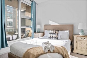 Ein Hotelzimmer mit Bett, Fenster, Nachttisch und Stuhl.