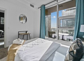 Ein Hotelzimmer mit einem Bett, einem Sessel, einem kleinen Tisch, einem Spiegel und einem Fenster mit Vorhängen.