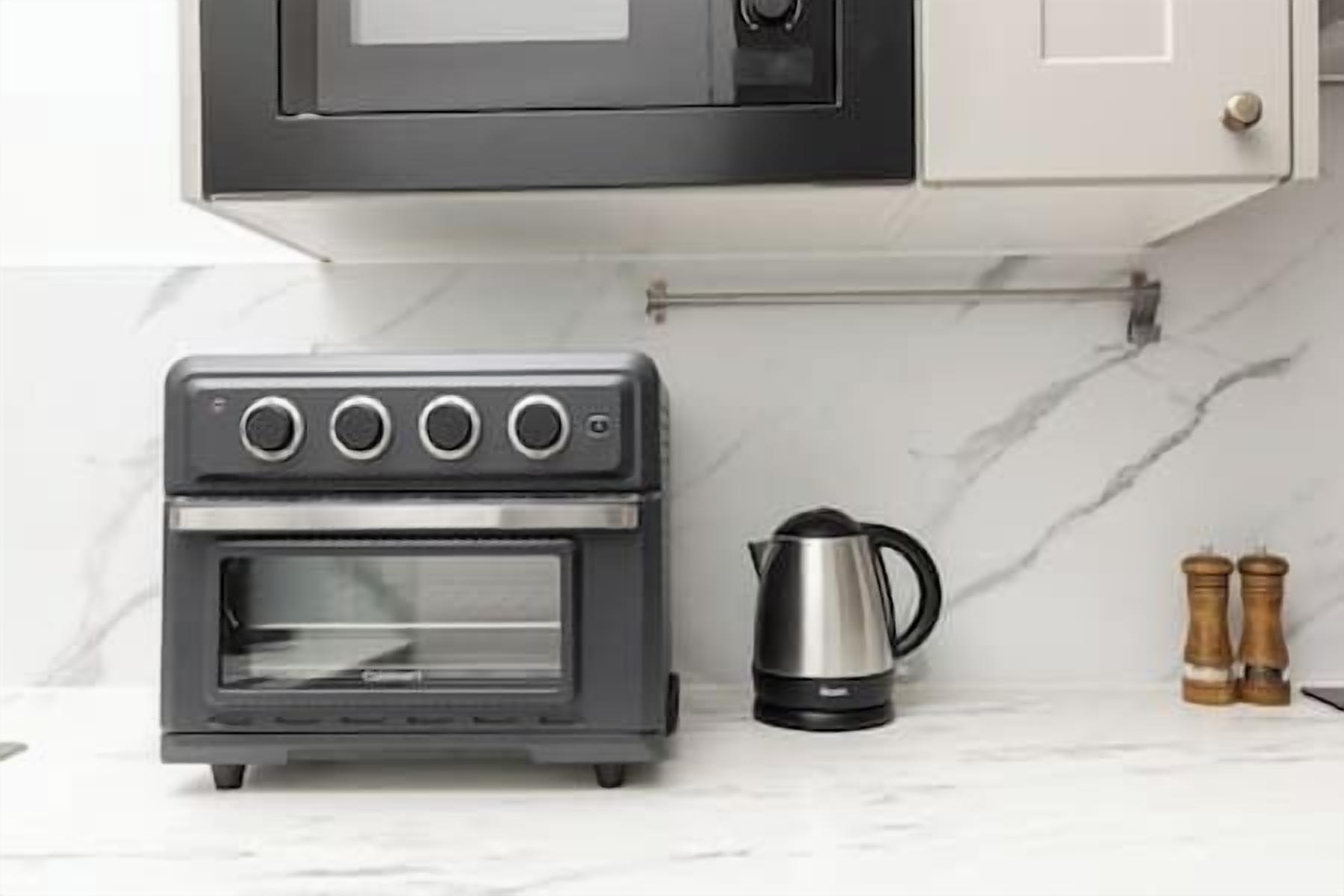 A compact kitchen with a built-in oven, a kettle, and salt and pepper shakers on the counter.