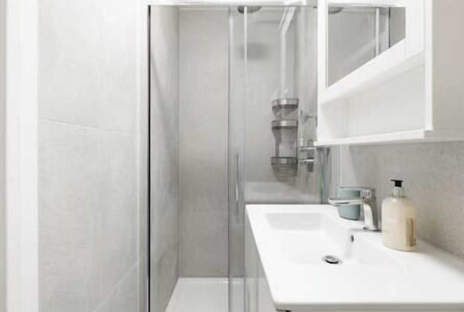 A modern bathroom with a glass shower enclosure, a white sink, and a mirror above it.