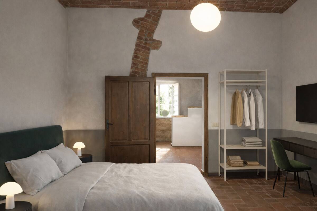 A bedroom with a bed, a wardrobe, a desk, and a chair.