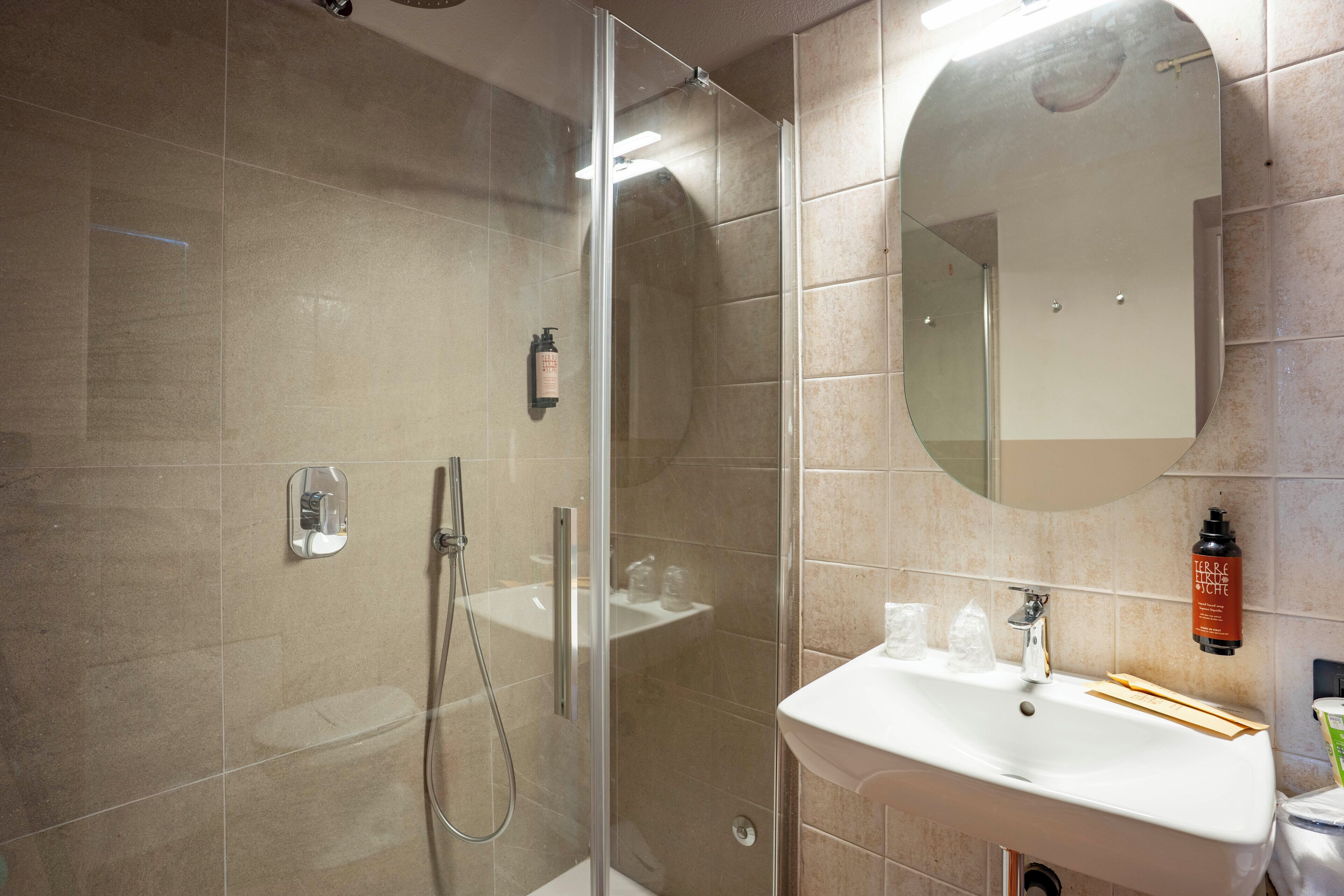 Un baño moderno con ducha envuelta en vidrio, un lavabo blanco y un espejo en la pared.