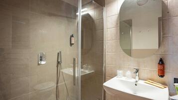Un baño moderno con ducha envuelta en vidrio, un lavabo blanco y un espejo en la pared.