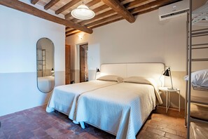 Una camera da letto con un letto matrimoniale, uno specchio, un comodino con una lampada e una cuccetta.