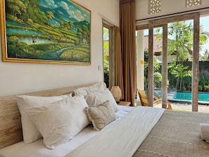 Une chambre d’hôtel avec un lit, un tableau représentant un paysage et une vue sur une piscine.