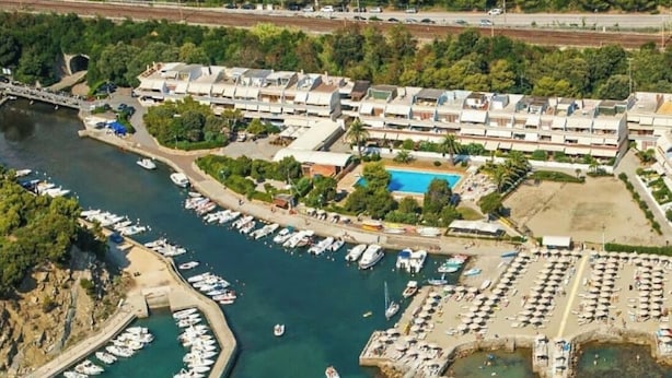 Vista aérea de una zona costera con un puerto deportivo, una piscina y un complejo residencial.