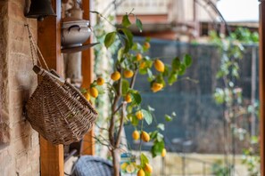 A wicker basket hanging on a brick wall, a potted plant with yellow flowers, and a glimpse of a building in the background. - 'Il Girasole -with Garden-' Apartment with Air Conditioning (Buonconvento)
