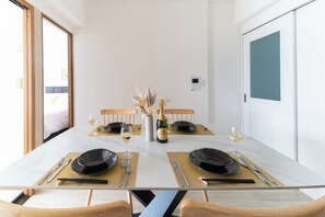 A dining area with a table set for two, including plates, cutlery, and glasses. - OPEN Sale! Walking distance from Umeda area / Easy access to Namba and Dotonbori / 10 minutes to USJ by train / Max. 8 people (Kita-ku, Osaka-shi)
