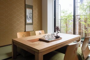 Un coin repas avec une table en bois, des chaises et un bonsaï.
