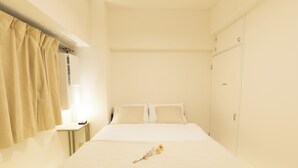 A neatly made bed with a single flower, a bedside table with a lamp, and a wardrobe in a minimalistic room. - OPEN Sale! Walking distance from Umeda area / Easy access to Namba and Dotonbori / 10 minutes to USJ by train / Max. 8 people (Kita-ku, Osaka-shi)