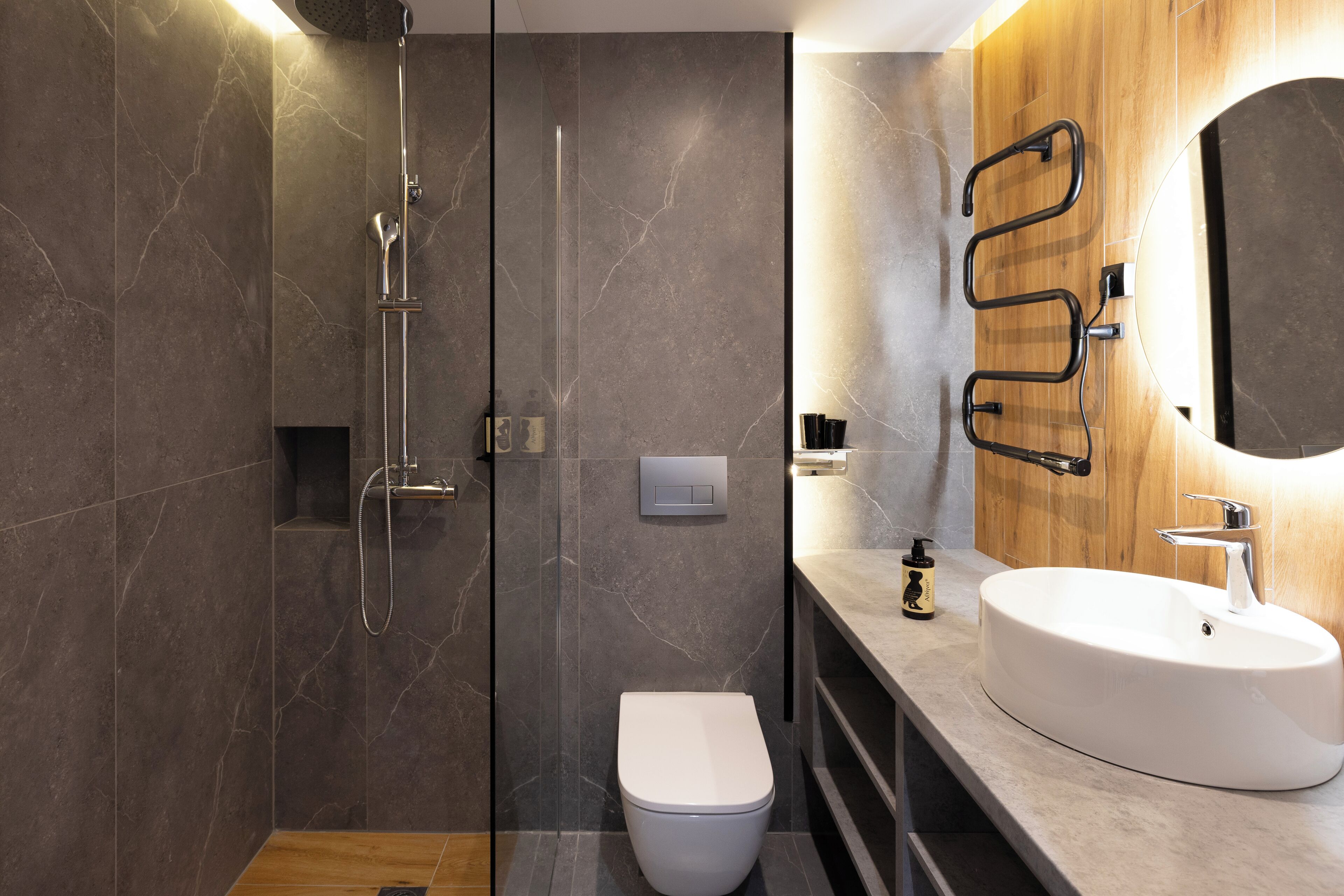 A modern bathroom with a glass-enclosed shower, a white toilet, a vanity with a sink, and a mirror.