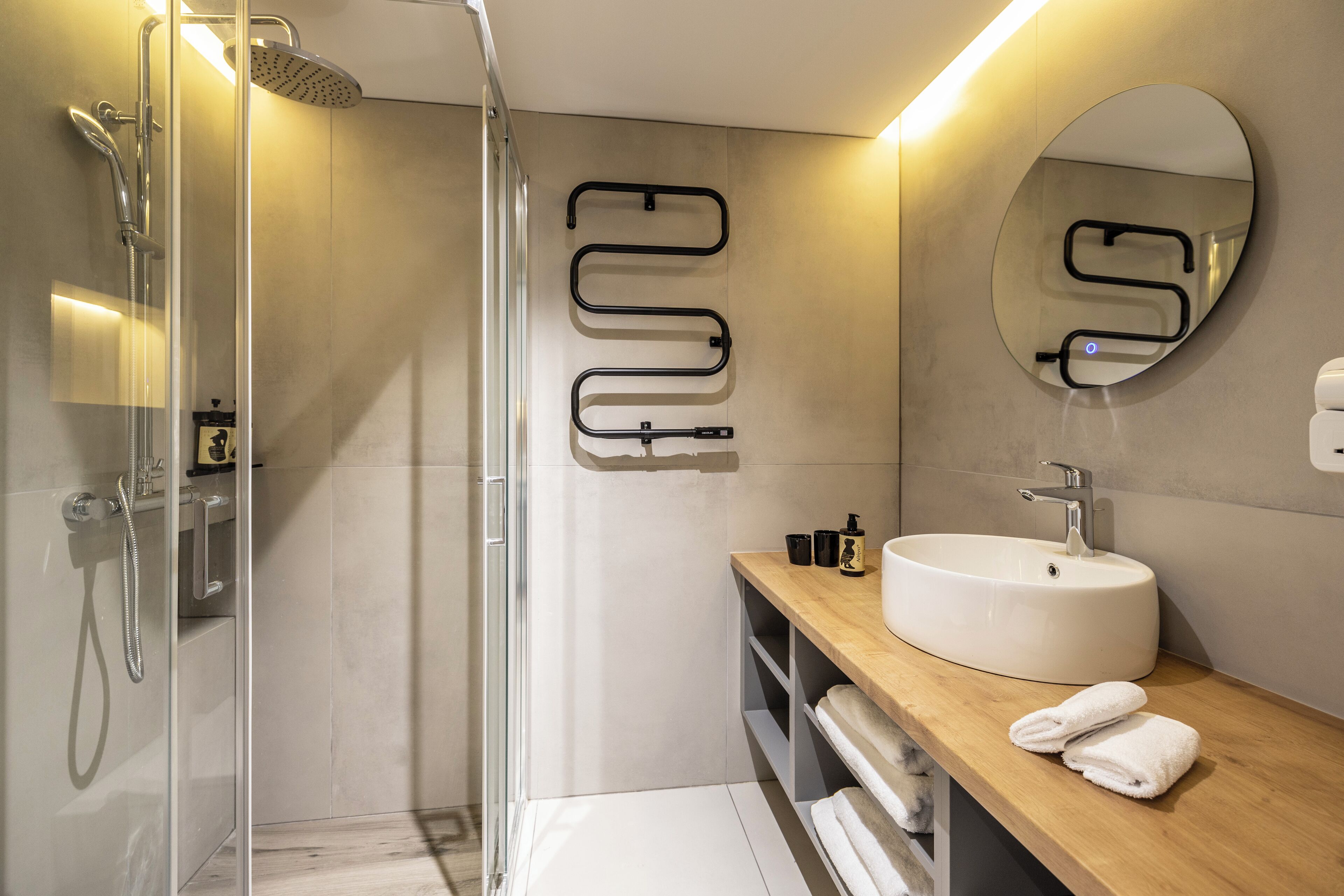 A modern bathroom with a glass shower enclosure, a wooden vanity with a sink, and a mirror.