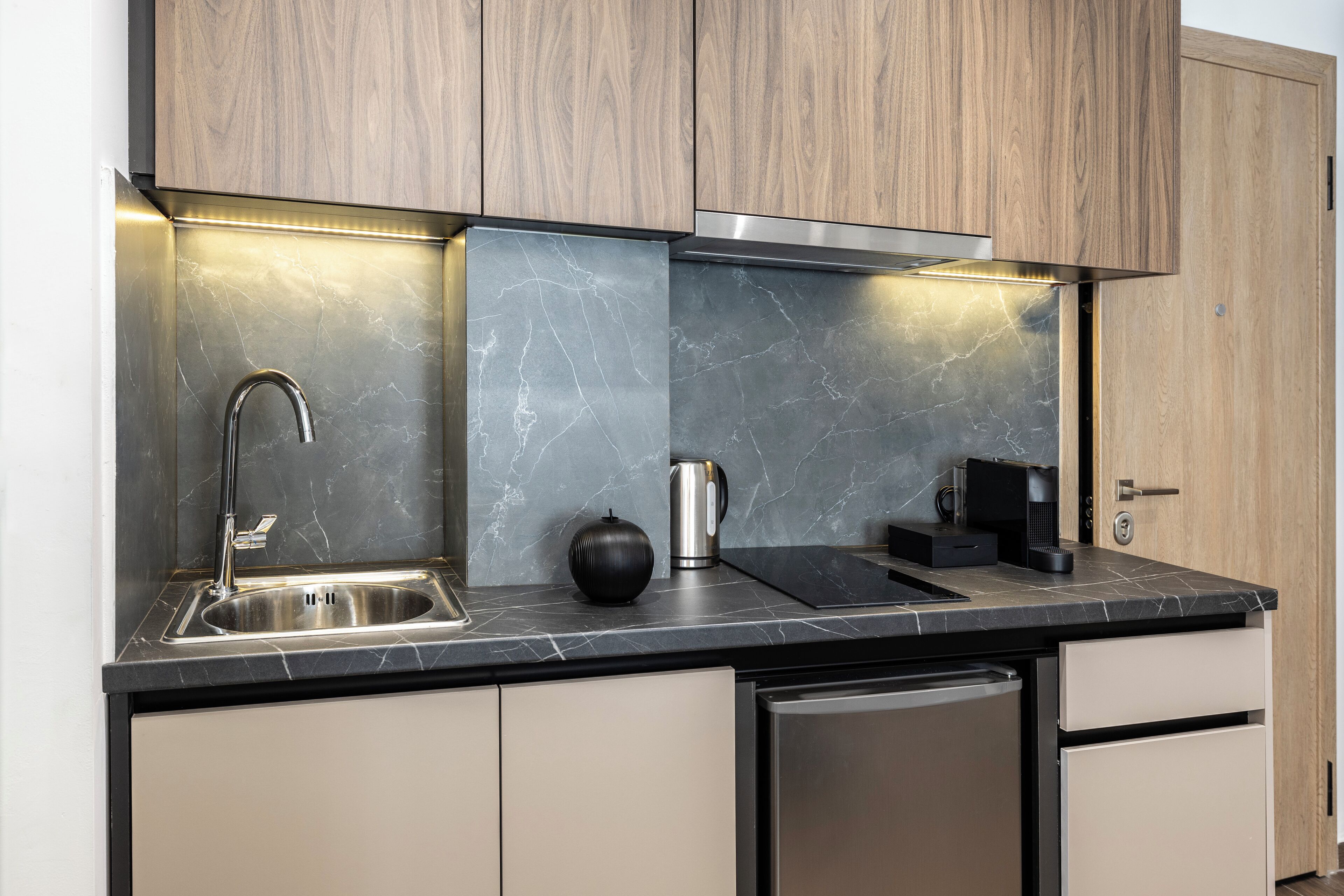 A modern kitchen with a stainless steel sink, a coffee maker, and a built-in oven.