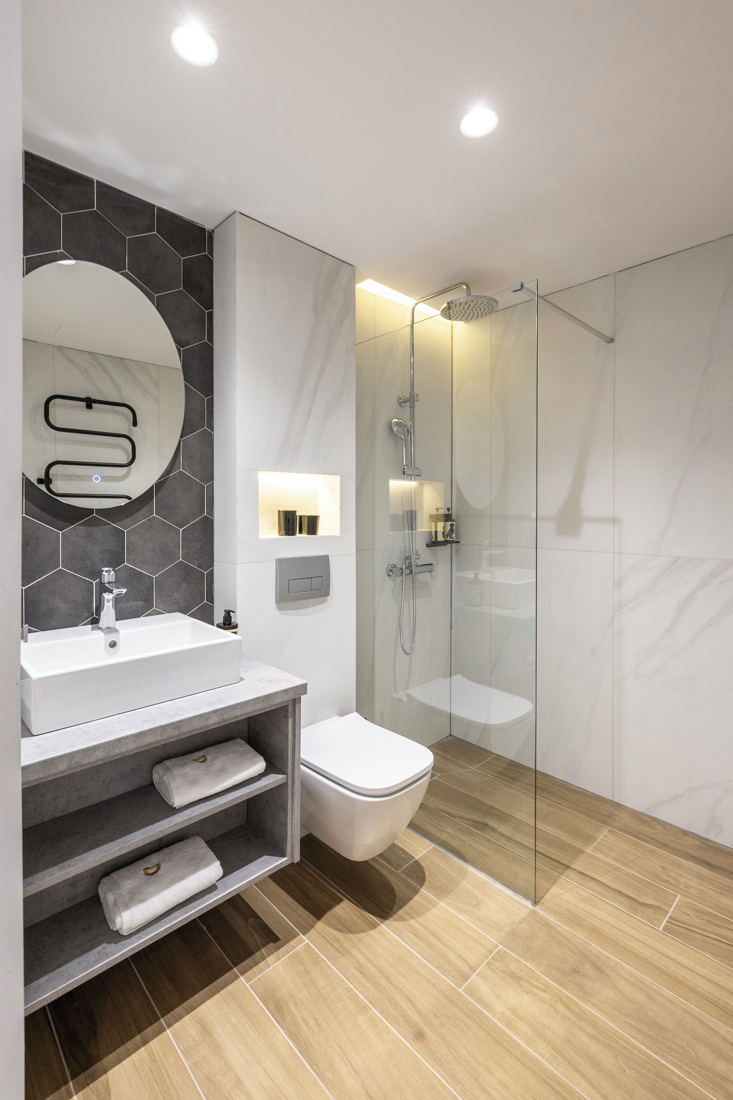 Ein modernes Badezimmer mit einer gläsernen Duschkabine, einem weißen Waschbecken und einem Boden aus Marmorfliesen.