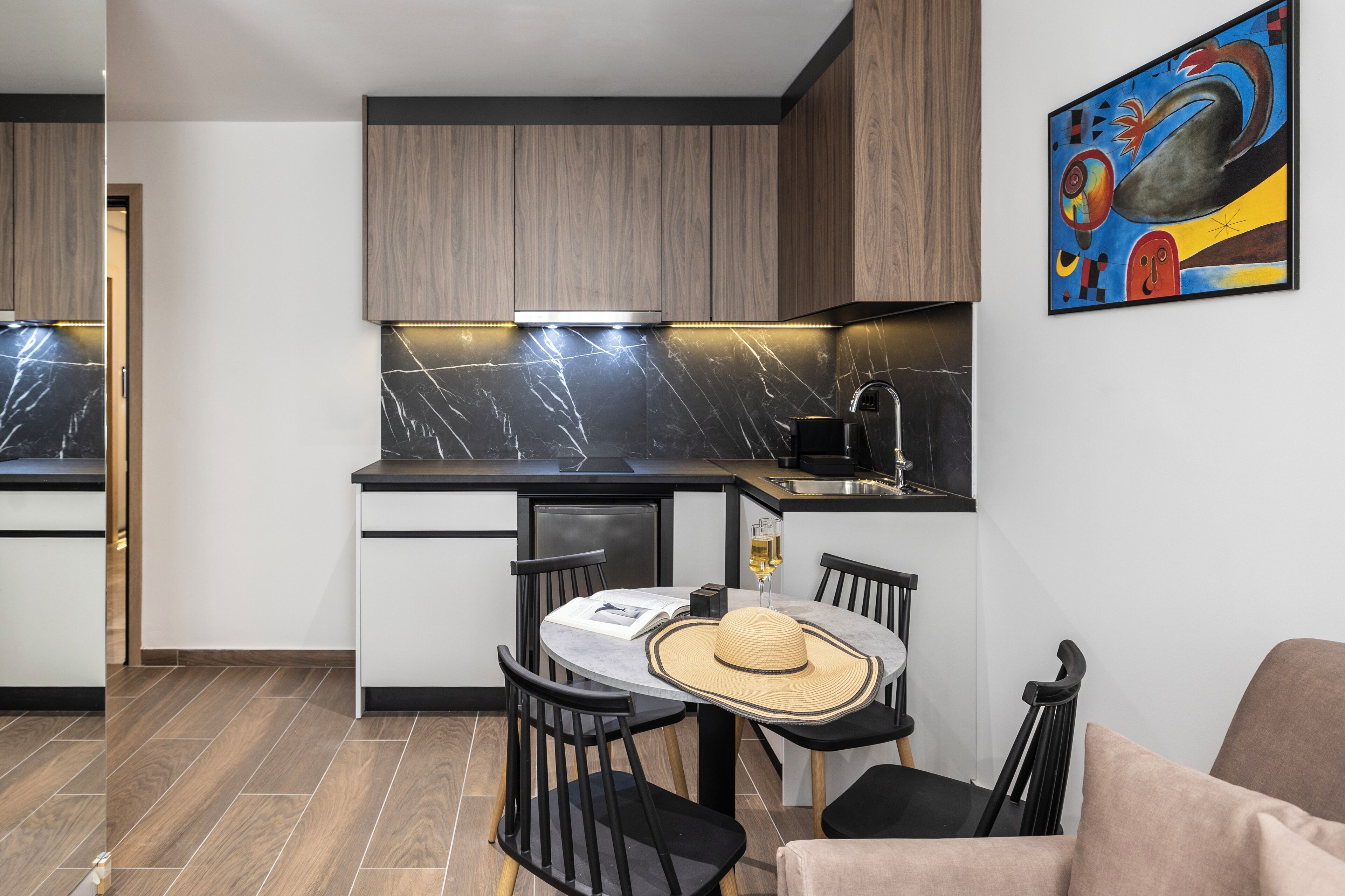 A compact kitchen with a dining area, featuring a marble backsplash, modern cabinetry, and a dining table with chairs.
