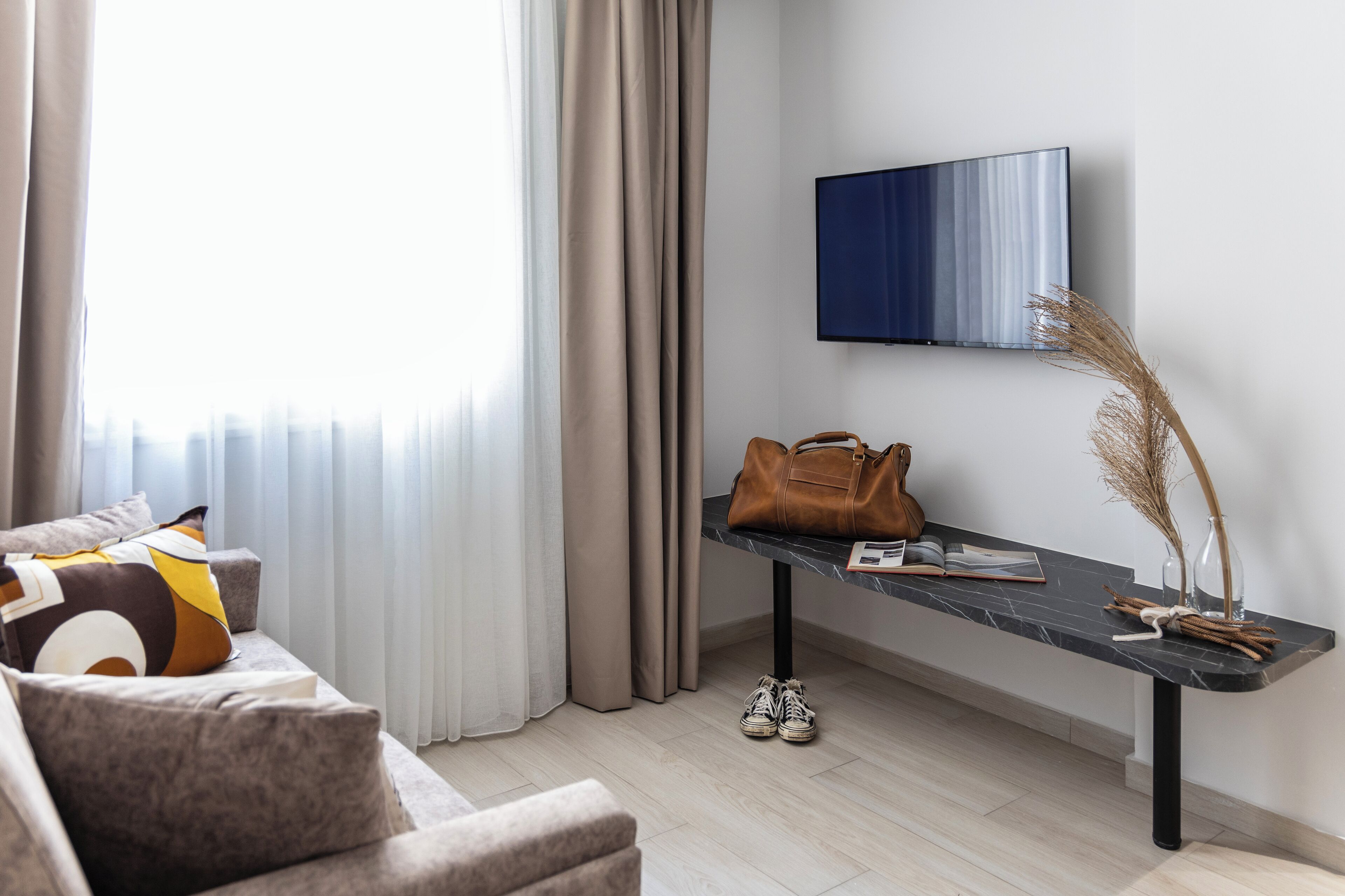 A modern living room with a sofa, a coffee table, a TV, and a window with curtains.