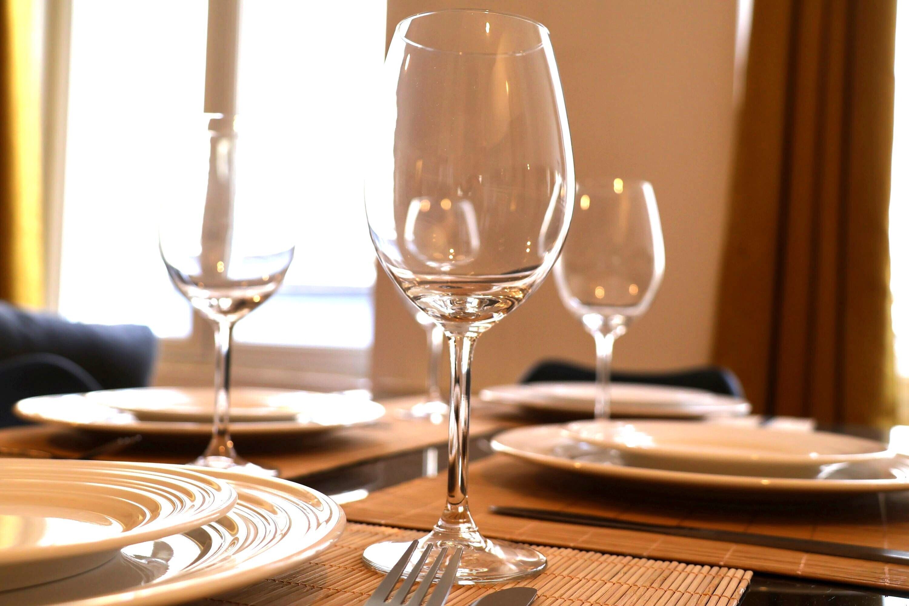 A dining table set with plates, cutlery, and wine glasses.
