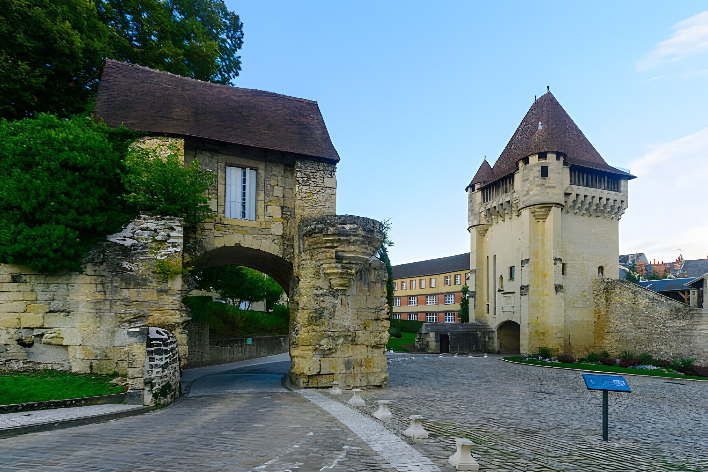 Un bâtiment historique en pierre, doté d’une tour, d’une arche et d’un pavage en pierres.