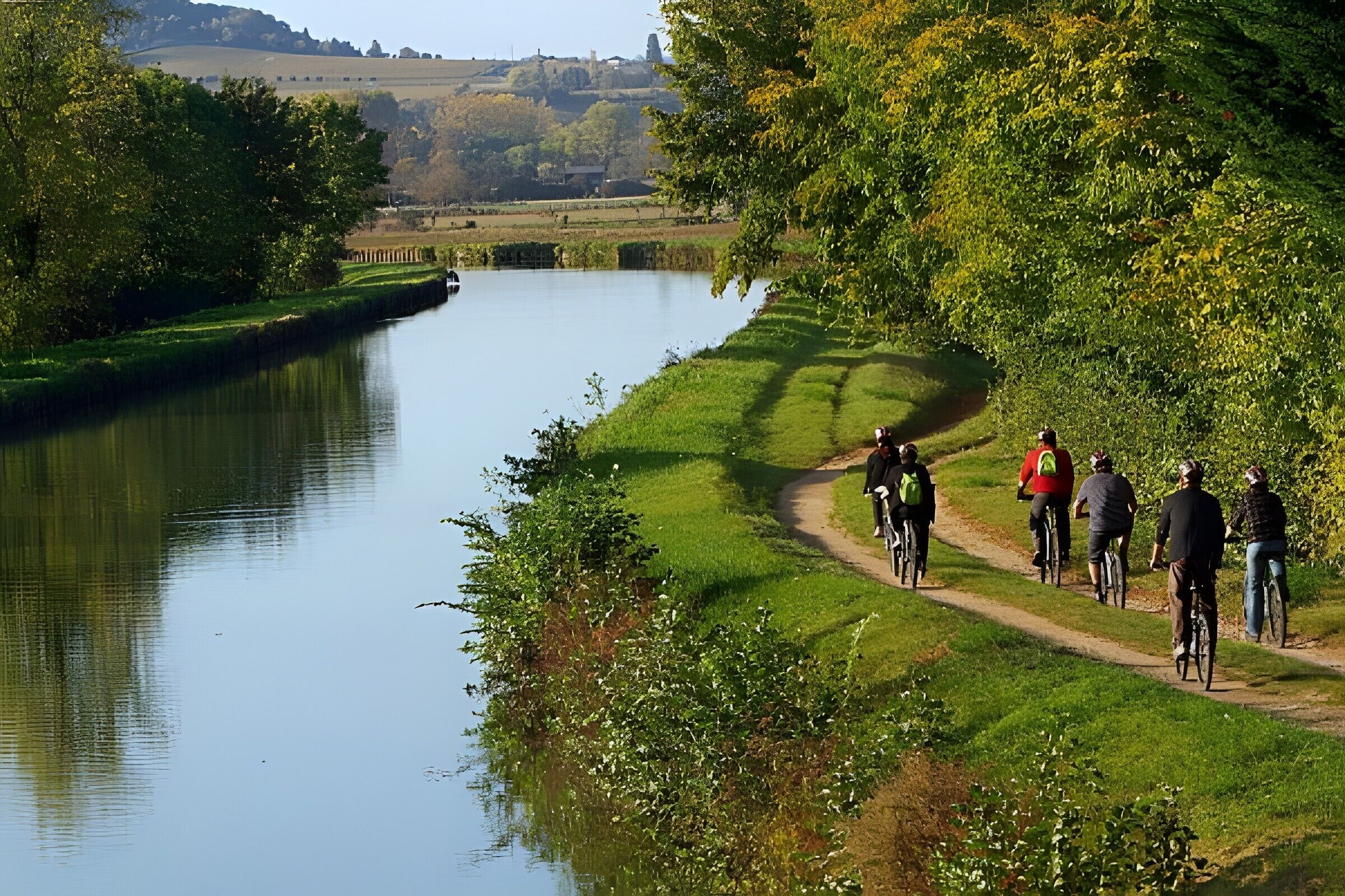 A river with cyclists on a path alongside.