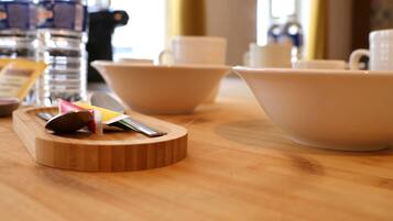 A wooden table with a cutting board, a spoon, and a packet of napkins.