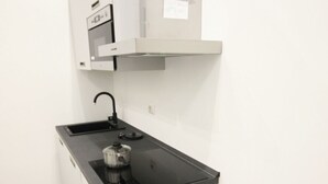 A compact kitchenette with a black countertop, a built-in oven, and a microwave. - Cuore di Trastevere (Rome)