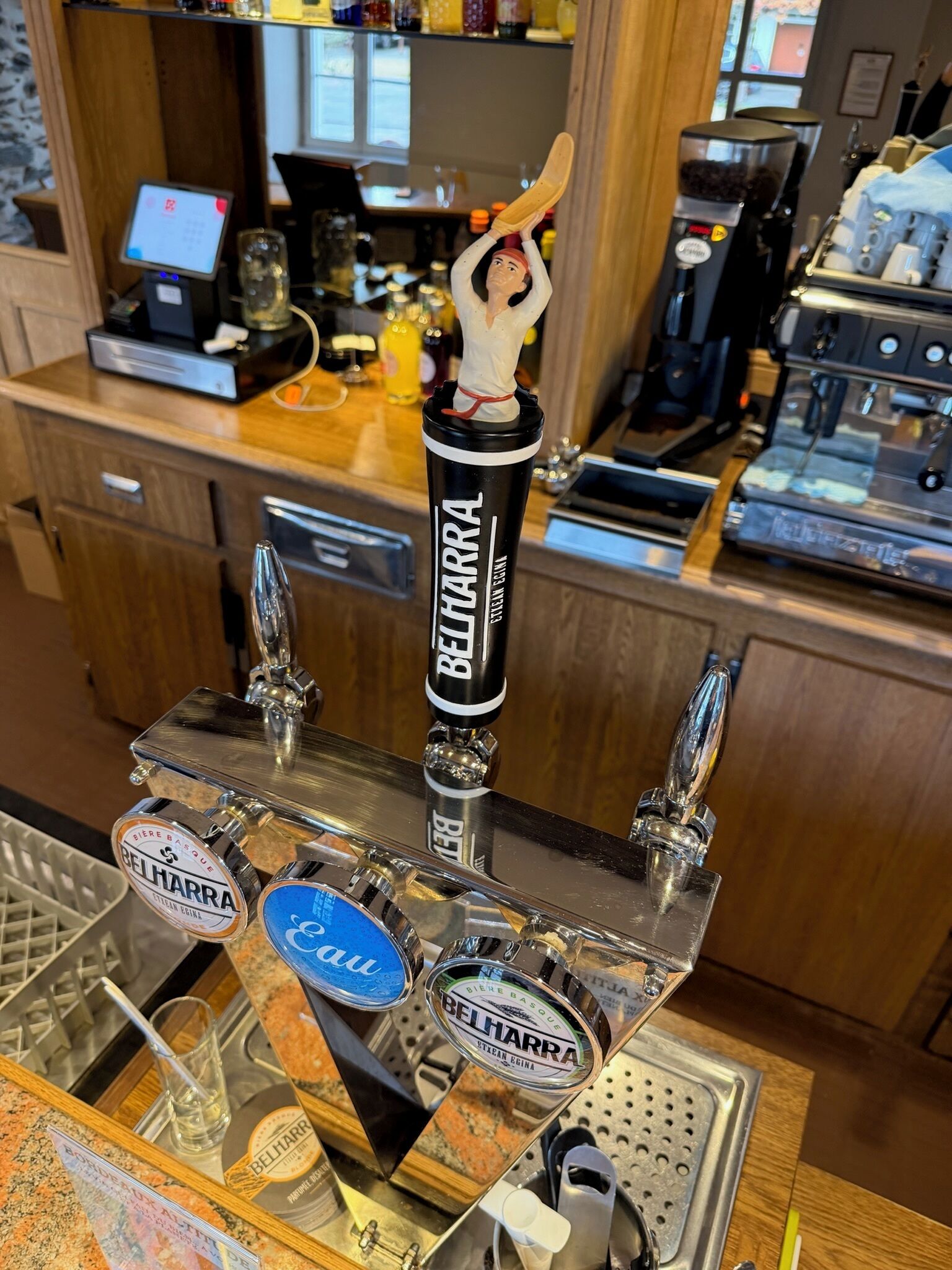 Zona de bar con una grifo etiquetado 'BELHARRA' y un grifo de cerveza con una figura sosteniendo una jarra.