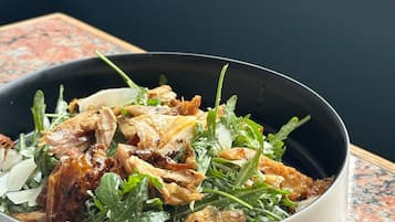 Eine Salatschüssel mit Grünzeug und Hähnchen auf einer Granitabdeckung.
