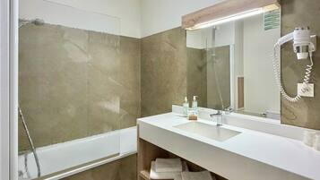 A modern bathroom with a glass shower enclosure, a white sink, a mirror, and a towel rack.