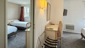 A hotel room with two single beds, a desk with a chair, a mirror, a TV, and a window with curtains. - HOTEL DE LA PAIX (Saint-Palais)