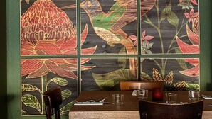 A dining area with a table set for two, featuring a wooden table and chairs, and a decorative wall with floral and bird patterns. - HOTEL DE LA PAIX (Saint-Palais)