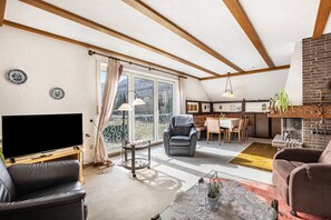 Ein Wohnzimmer mit Fernseher, Sofa und Essbereich mit Blick.