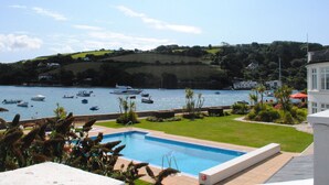Une piscine offrant une vue sur les bateaux sur l’eau et sur les collines en arrière-plan.