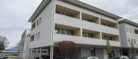 A multi-story building with a parking area in front.