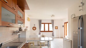 A modern kitchen with wooden cabinets, a marble countertop, and a central island with stools. - Casa Leo by Wonderful Italy (Olbia)