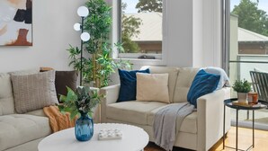 Una sala de estar moderna con una mesa de centro redonda blanca, un sofá color beige y un ventanal con vistas al exterior.