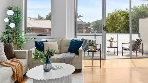 Un salón moderno con un sofá, una mesa de centro y un balcón con mobiliario exterior.