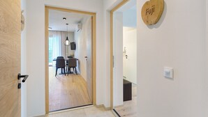Een gang met een houten deur, een wandlamp en een houten bord in de vorm van een hart met de tekst 'Fuji'.