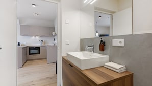 Een moderne badkamer met een grote spiegel, een houten wastafelmeubel en een witte wastafel.