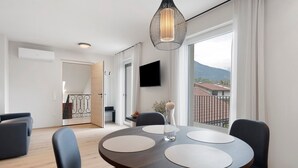 A modern dining area with a round table, four chairs, a hanging light fixture, and a view of the outdoors. - Apartment 'Pink Lady' with Mountain View & Large Balcony (Lana)